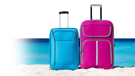 Kleiner blauer Koffer und großer Koffer in pink am Sandstrand