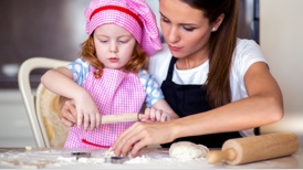 Au pair baking with a little girl in a checked apron